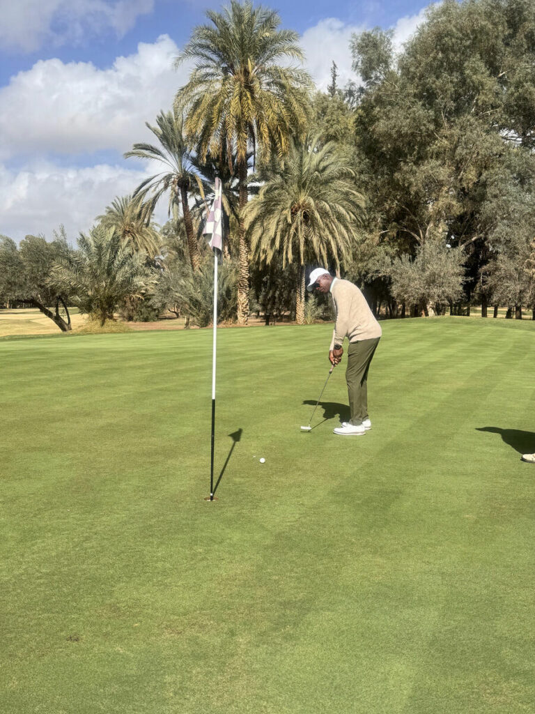 Un golfeur au putting sur un green bordé de palmiers à Marrakech