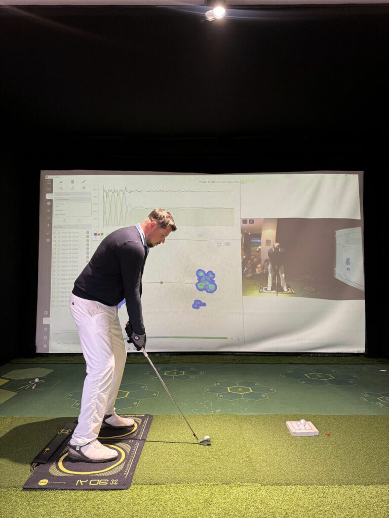 Un joueur sur la plaque de force, face à l'écran TrackMan, au G.Spot Golf Marrakech
